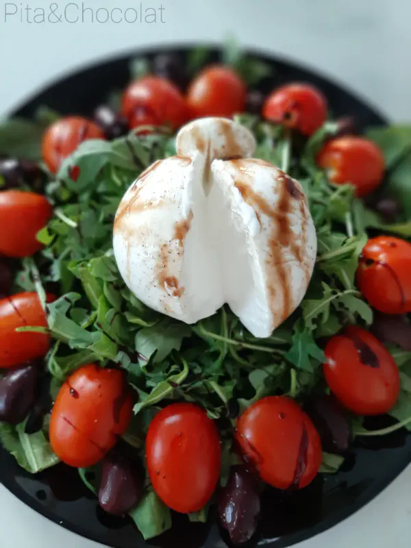 Burrata with cherry tomatoes on arugula bed